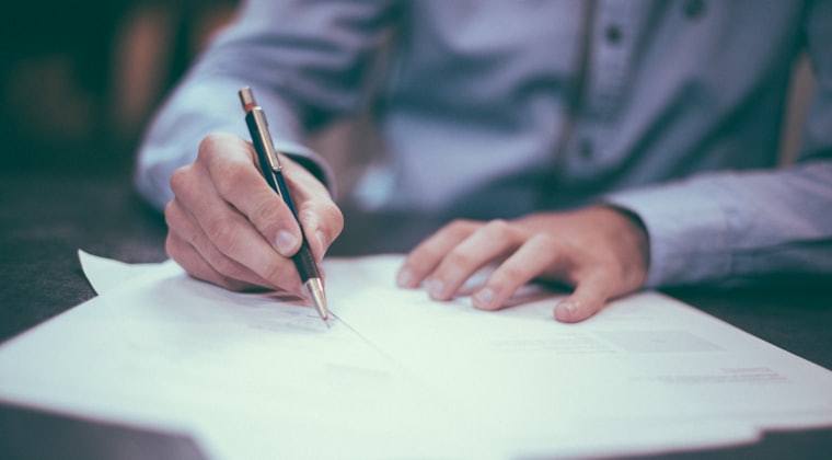 Hands writing on a printed proposal document