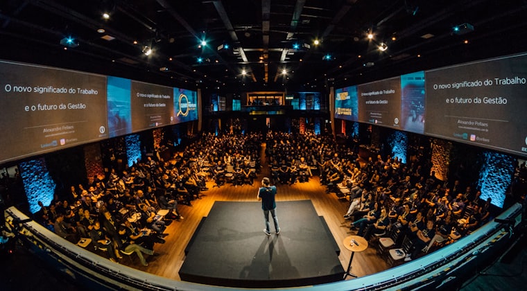 A speaker on stage addressing a full auditorium